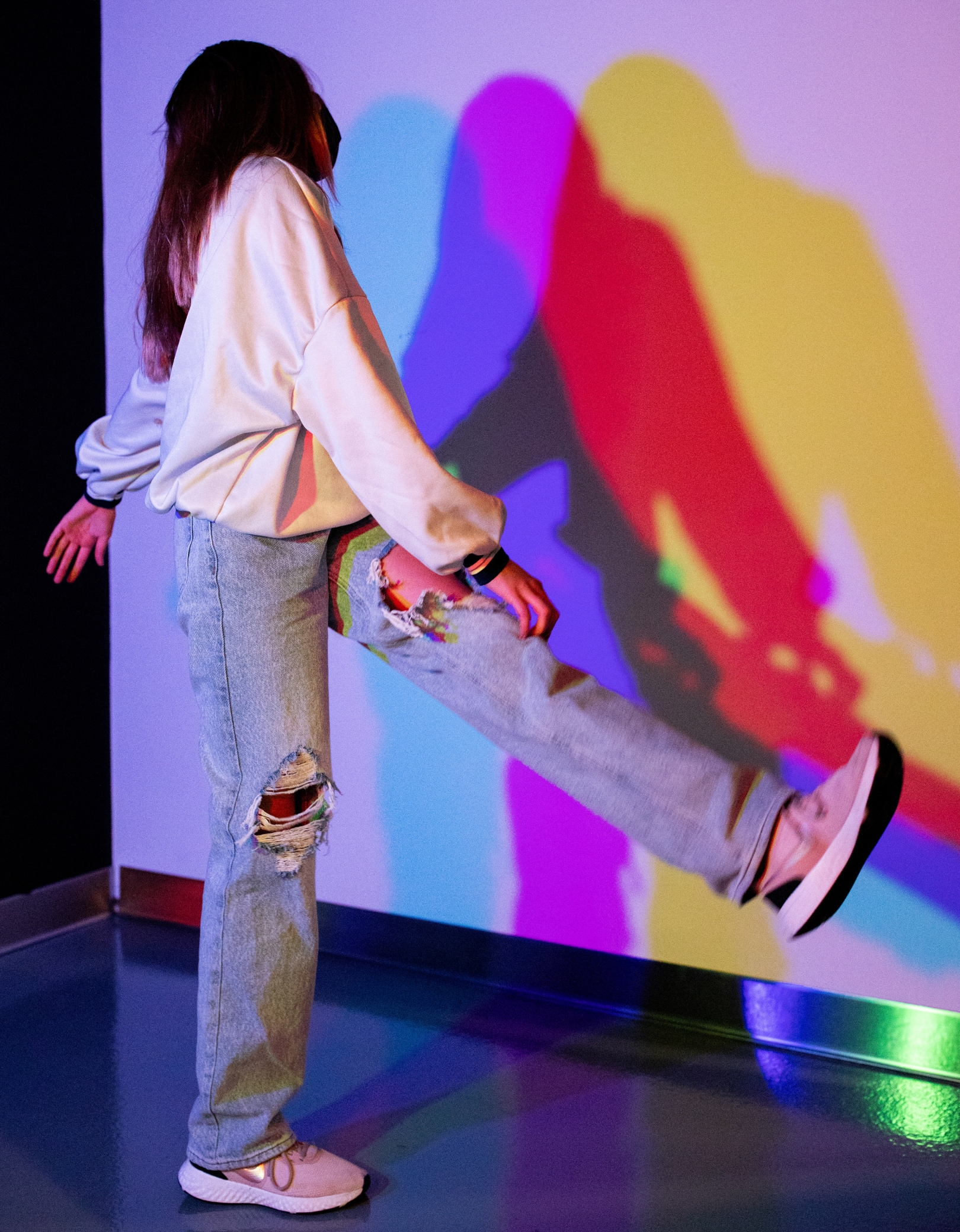Mädchen im Color Room des Museum der Illusionen Hamburg erzeugt farbige Schatten durch Lichtprojektion in Rot, Grün und Blau