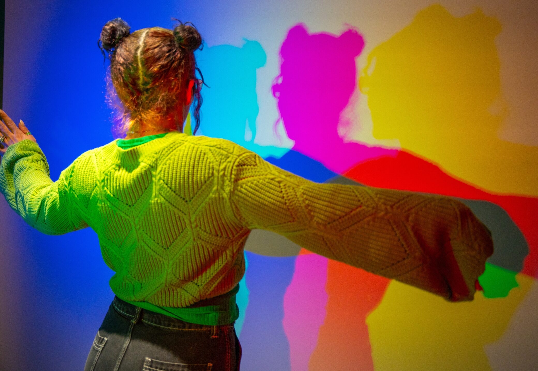 Girl in the Color Room at the Museum of Illusions Hamburg creating colorful shadows through red, green, and blue light projection