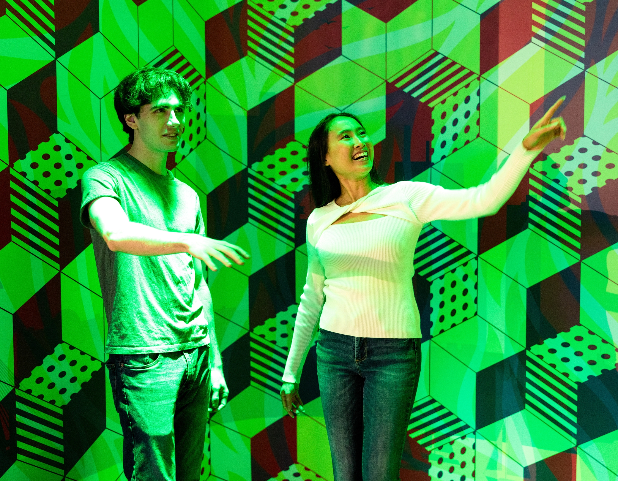 Ein Mann und eine Frau stehen im farbigen RGB-Raum des Museums der Illusionen Hamburg und schauen fasziniert auf die sich im Licht wechselnden Muster an der Wand.